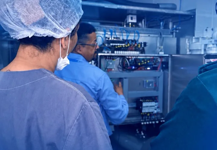 Técnico da Tesla no painel de um equipamento, acompanhado pela equipe do hospital
